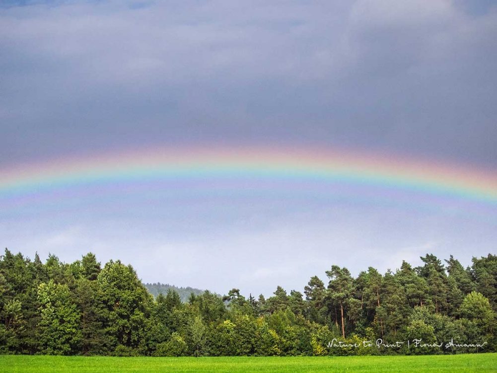 Vom Liegestuhl aus fällt der Blick auf einen Regenbogen